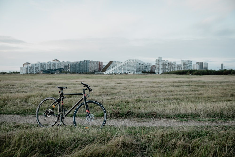 bike parked at the side of dirt road in the middle of grass field during day