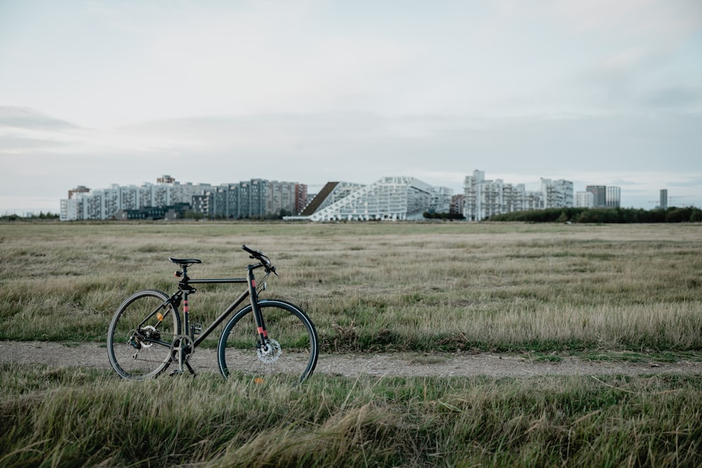 Bicicleta estacionada al costado del camino de tierra en medio del campo de hierba durante el día