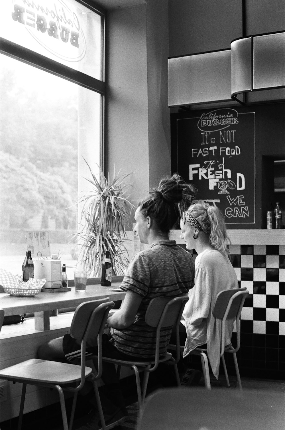 two women sitting beside table facing full-lite window inside shop