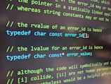 Text written on a computer screen displays programming code with comments. The code uses C syntax, featuring the use of 'typedef' to define character constants. Some text appears in green, suggesting it is a comment, while other code is in blue and white, indicating keywords and standard text respectively.