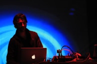 Technician programming a forestry machine ECU using a laptop with cyan blue interface lights.