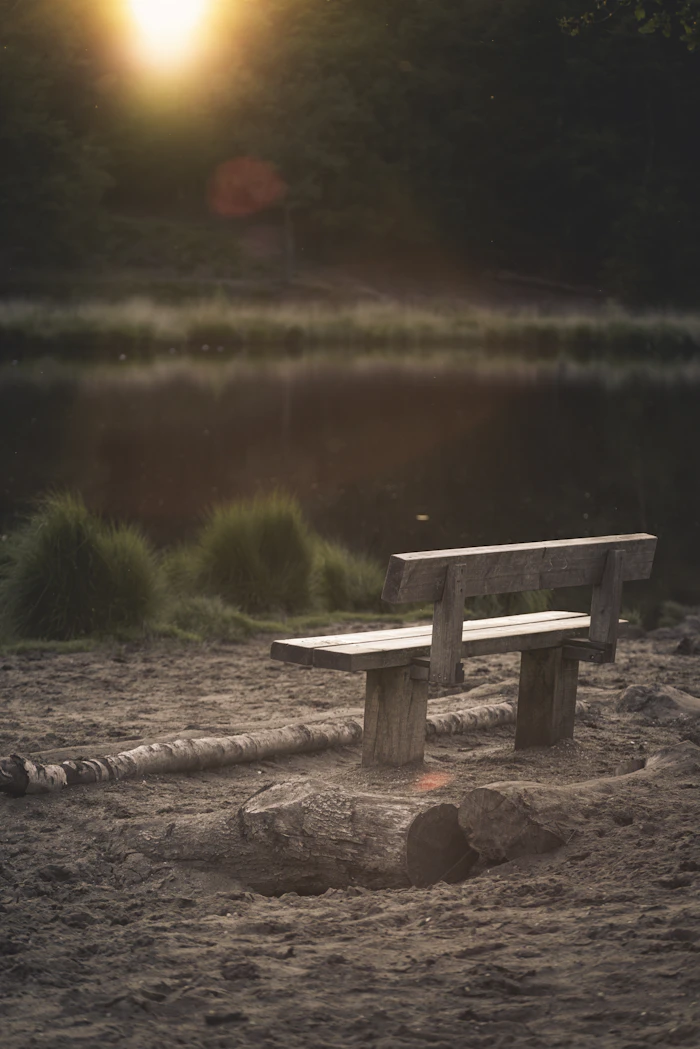 A wooden bench in front of calm water, on time and being in sync