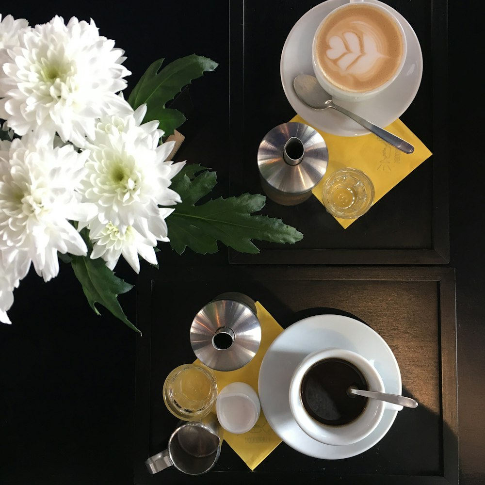 cup of coffee beside white flowers