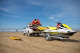 a truck with a boat on the back of it on a beach