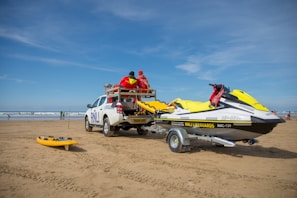 a truck with a boat on the back of it on a beach