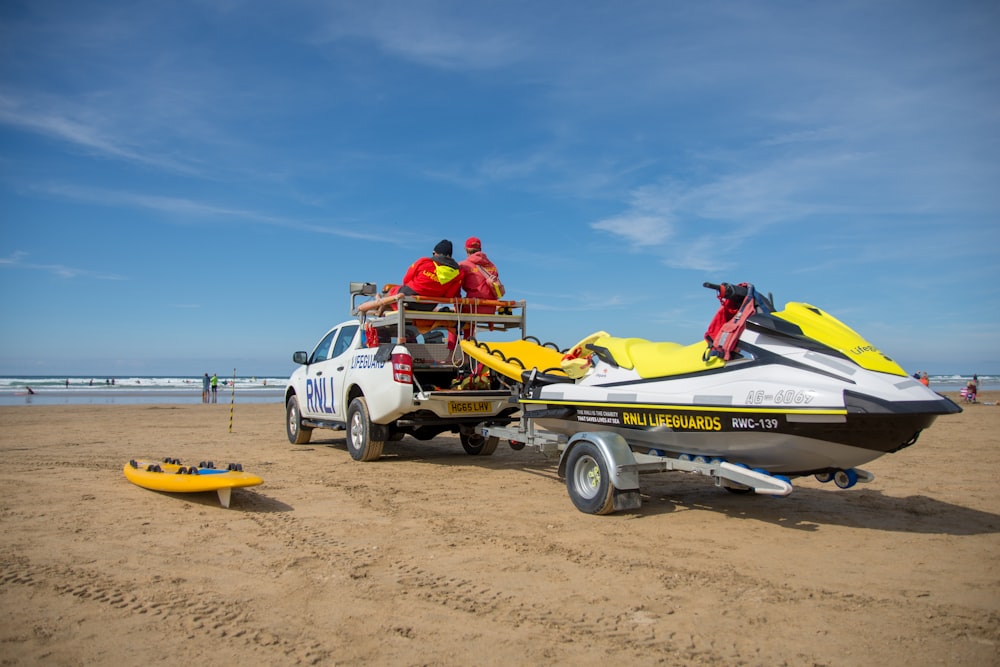 un camión con un bote en la parte trasera de él en una playa