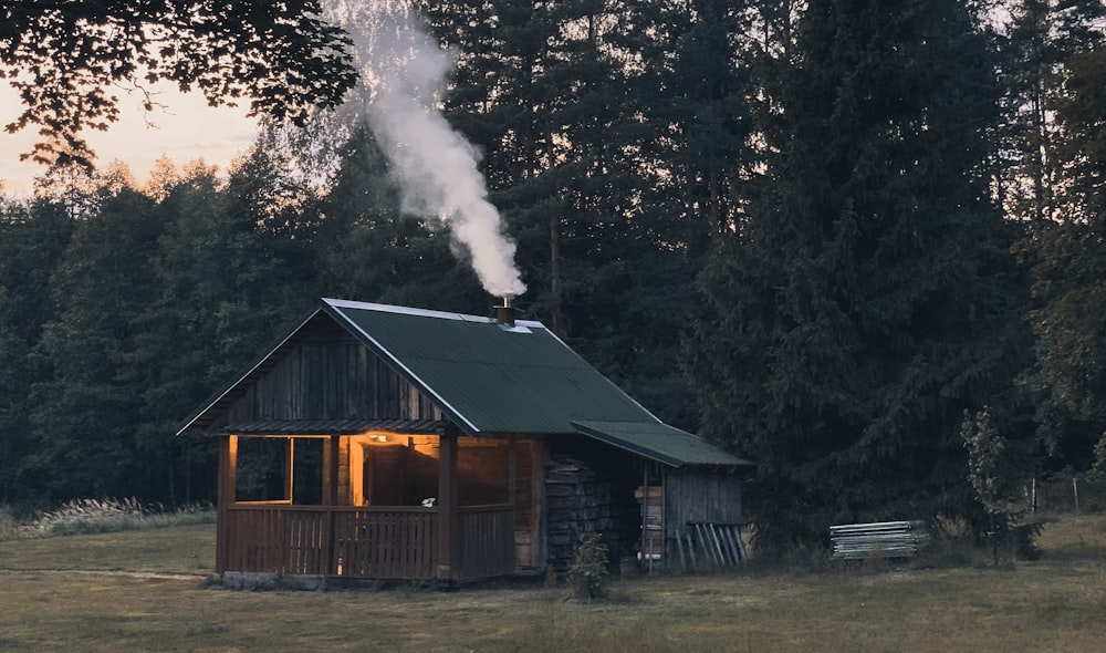 Cabaña con humo saliendo de la chimenea cerca de los árboles