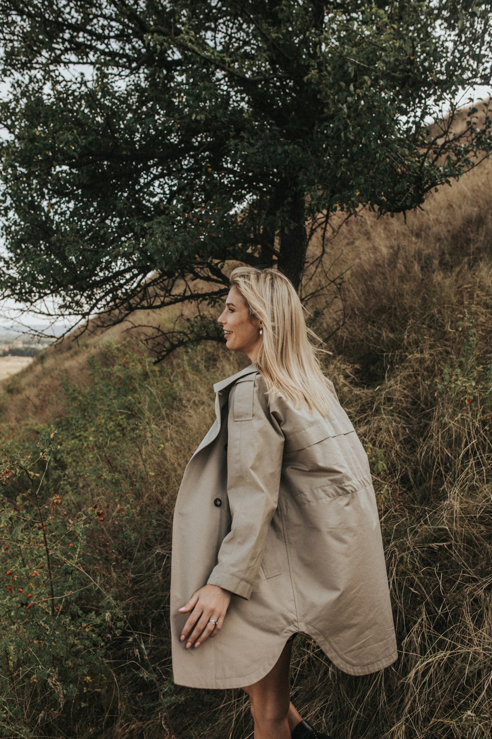 woman in gray jacket near green tree