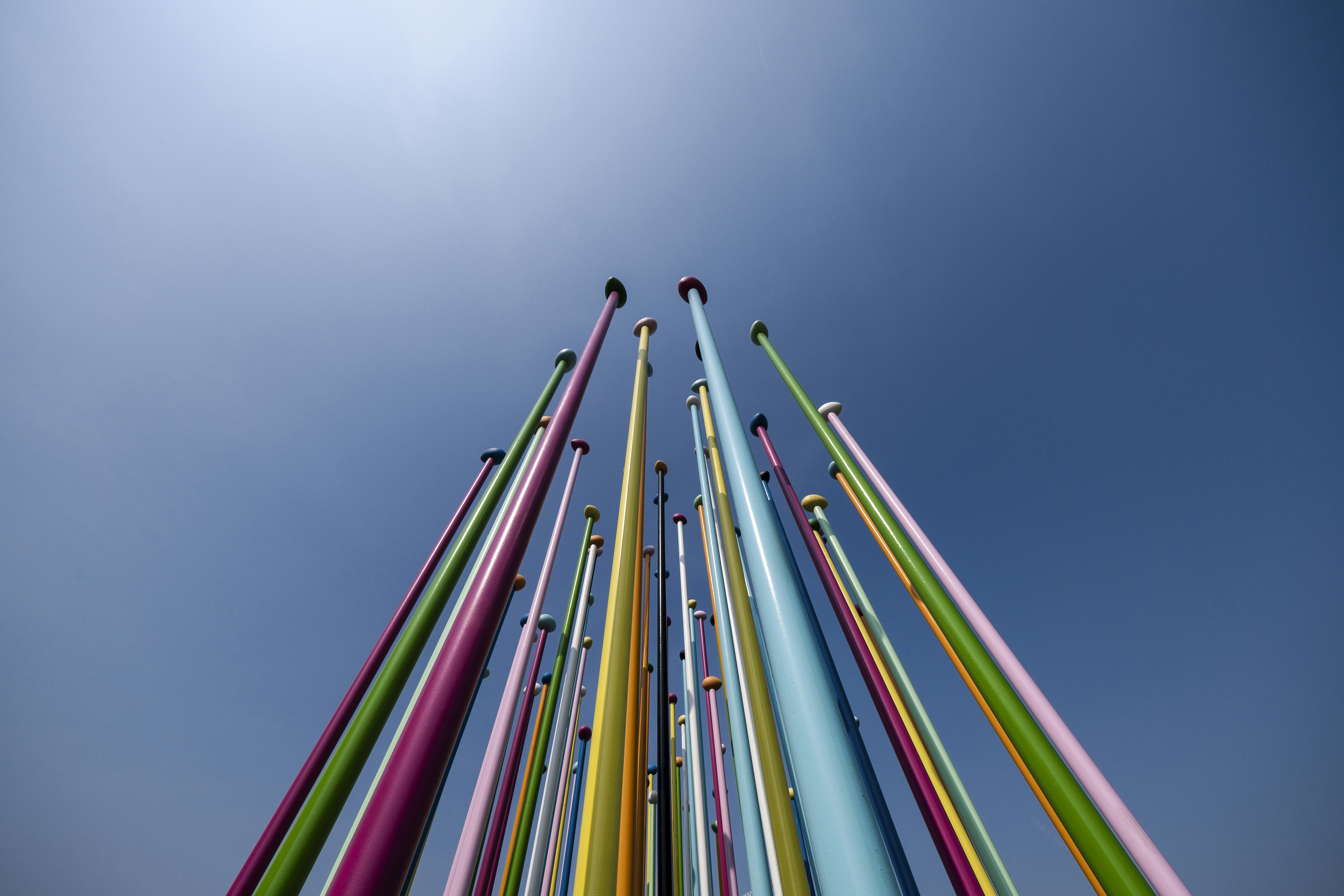Foto zum Thema Eine hohe mehrfarbige stange mit einem blauen himmel im