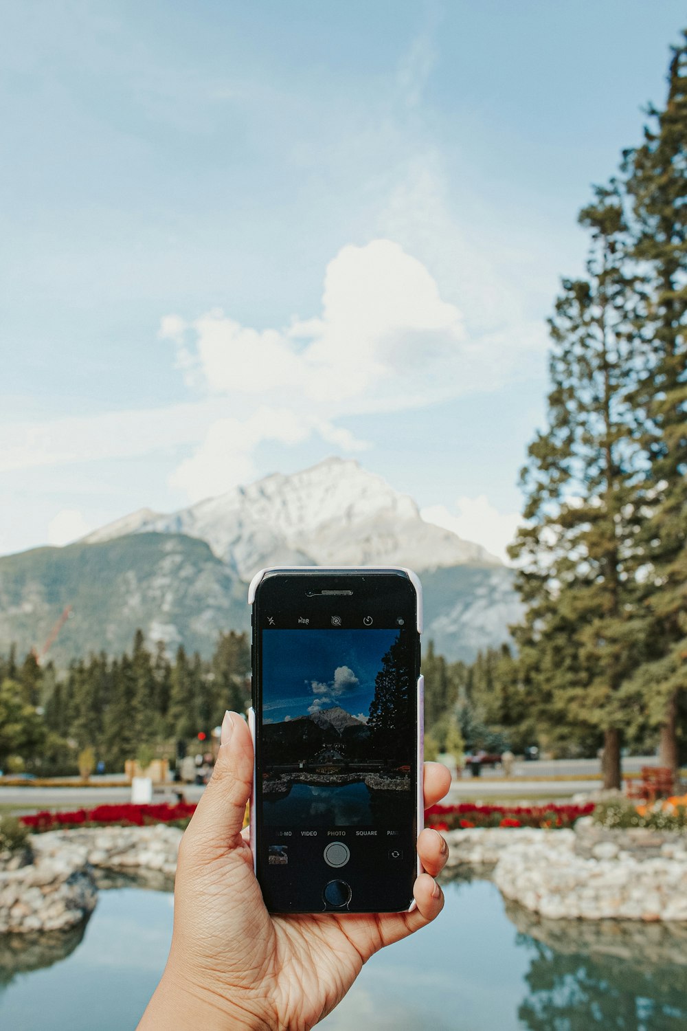 a person holding a cell phone in front of a lake