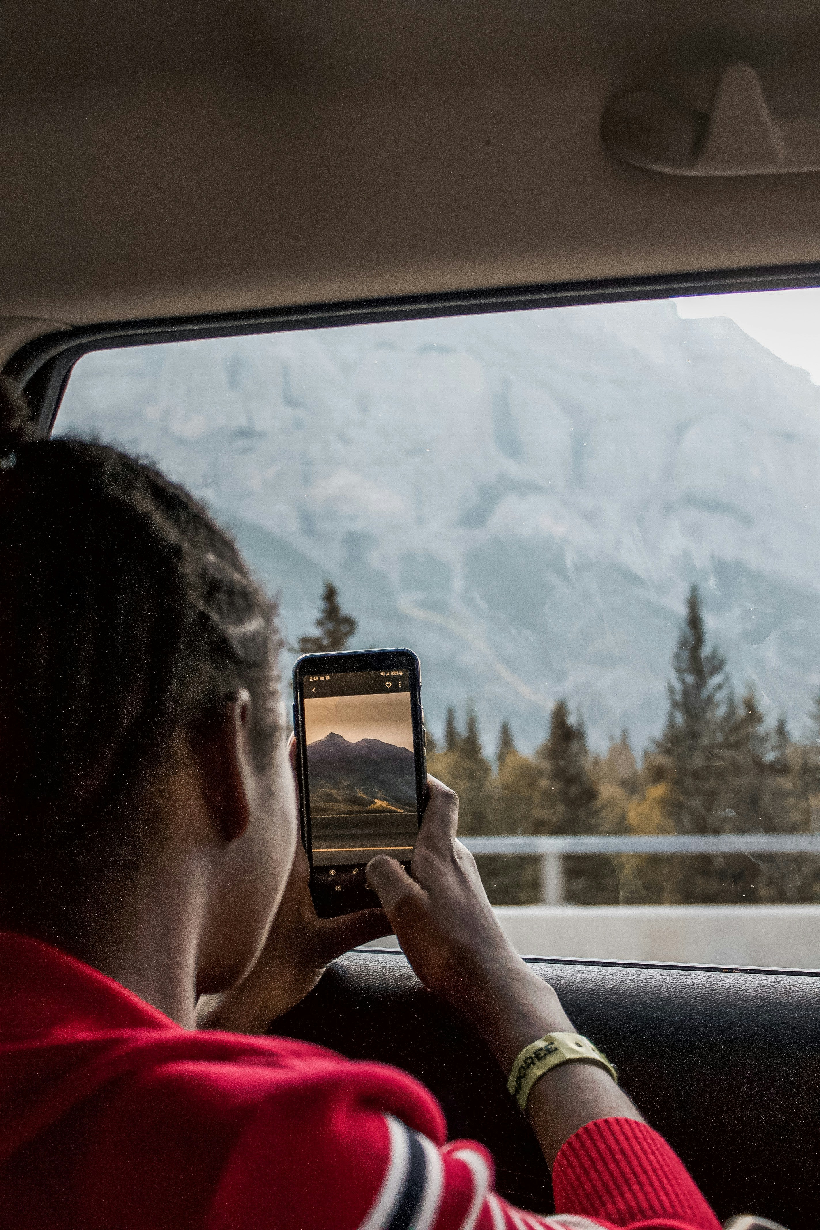 person holding black smartphone taking photo of brown mountain