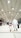 Several people are walking under a large, illuminated structure with a high ceiling. The walkway is spacious and well-lit by numerous overhead lights. The focus is on an adult and a child holding hands, both wearing traditional white garments commonly associated with pilgrimage.