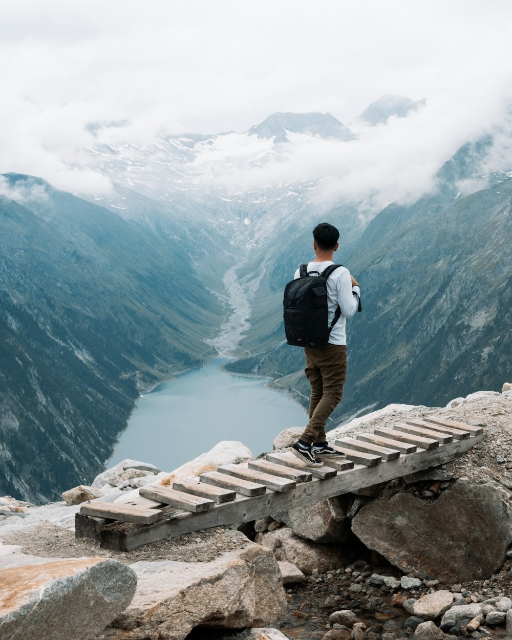 man walking on wooden bridge during daytime