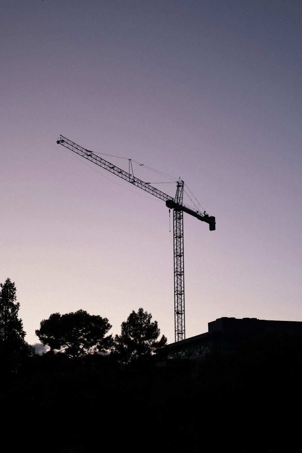 a crane is silhouetted against a purple sky