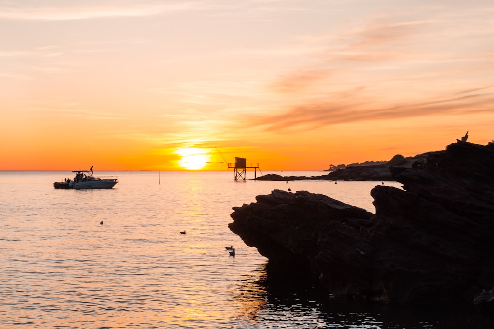 silhouette of boat on body of water during daytime