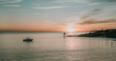 Sunset over the calm Black Sea with a silhouette of a small fishing boat near Sunny Beach.