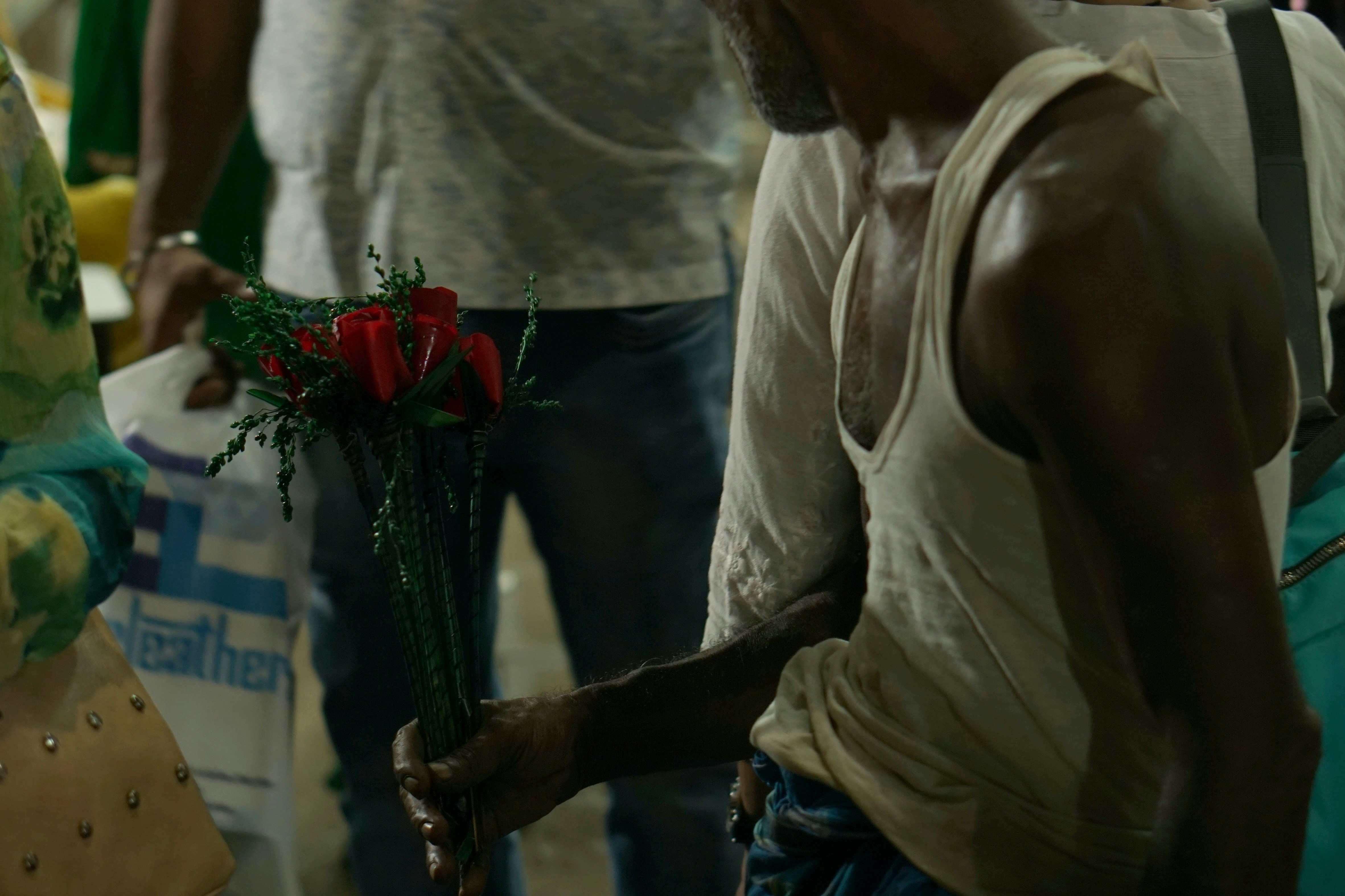 man holding red petaled flowers