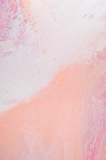 A soft blend of pastel colors with a prominent focus on pinks and whites. The texture appears marbled, with subtle swirls and bubbles creating a soothing abstract pattern.