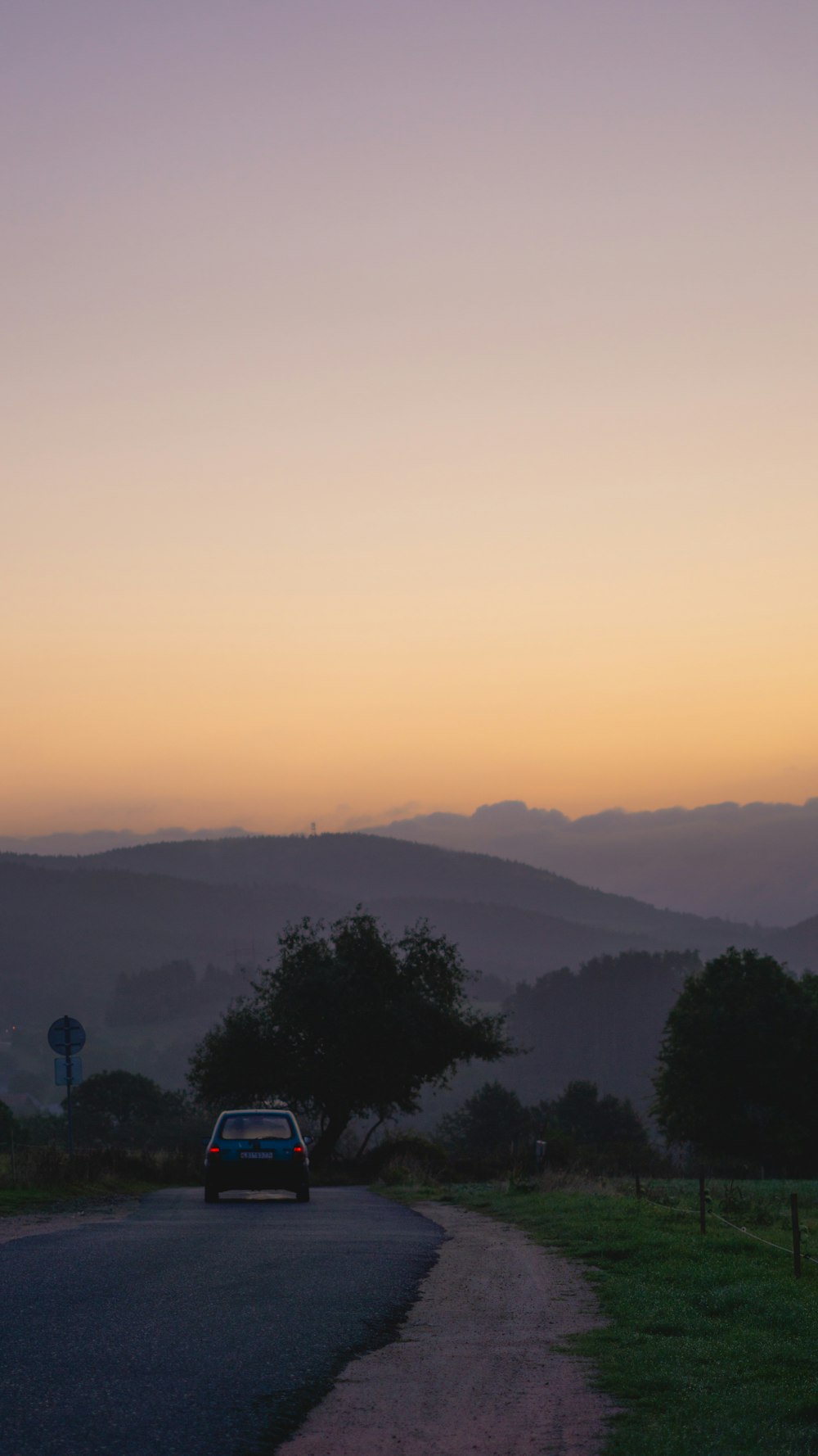 a car driving down a road with mountains in the background