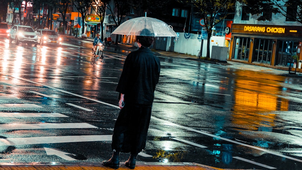 Mann, der auf der Straße steht, während er einen Regenschirm hält