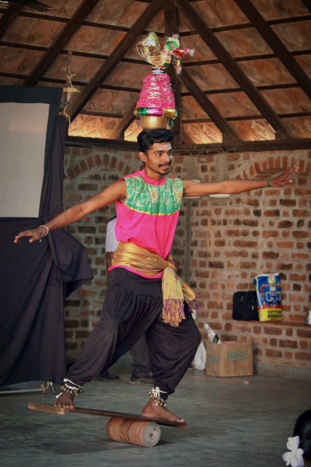 man balancing on board with jar on head