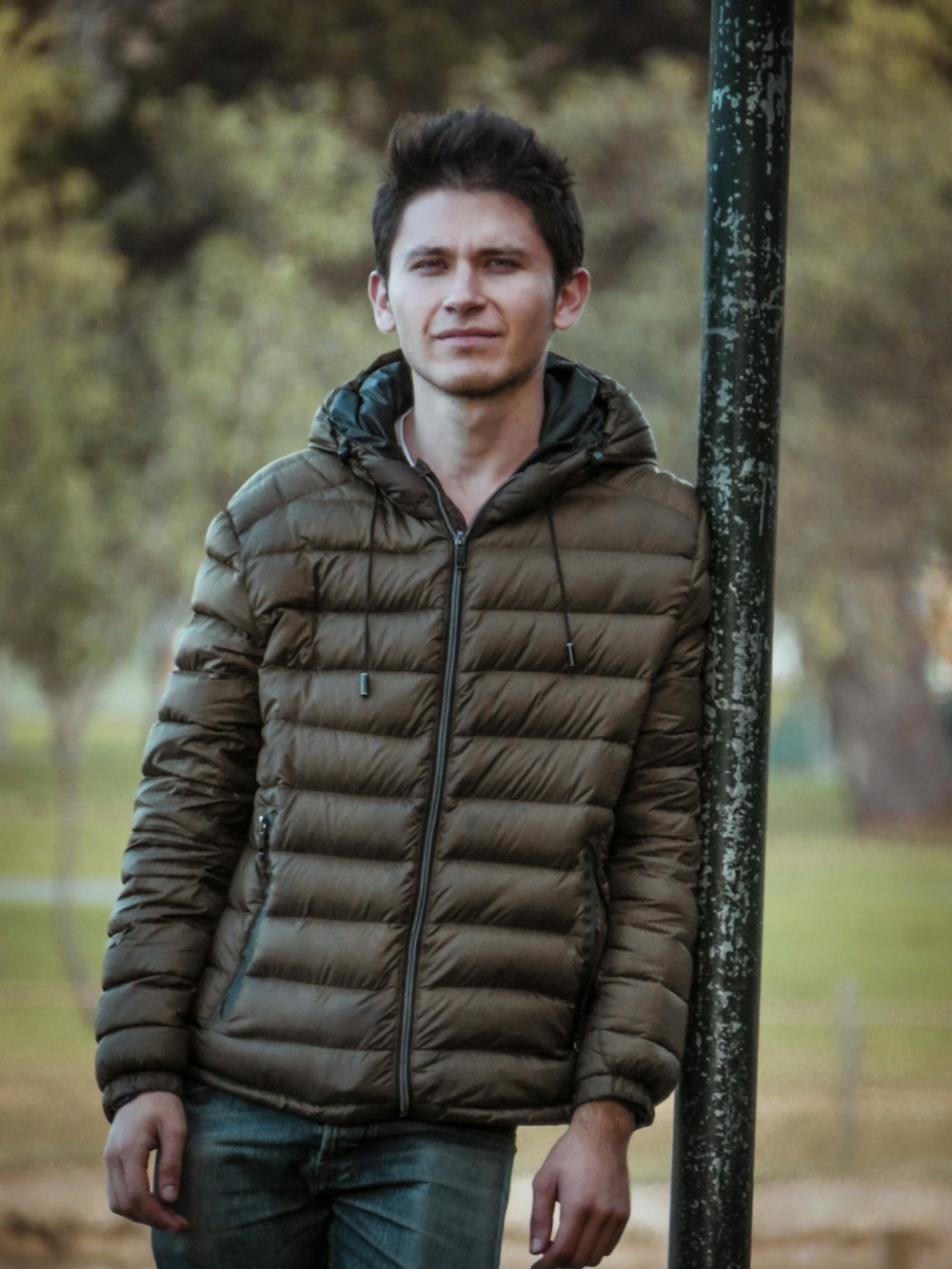 a man standing next to a pole in a park