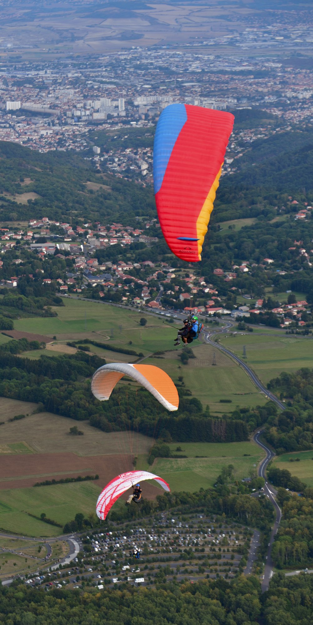 a group of people parasailing over a lush green countryside