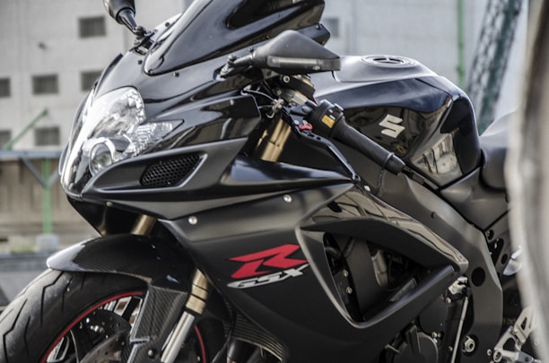A sleek Suzuki two-wheeler parked inside a clean, modern dealership showroom with blue and white branding.
