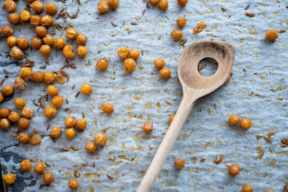 brown wooden spatula with hole beside seeds