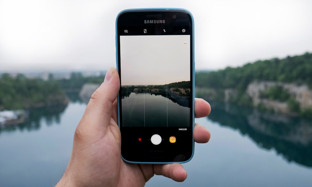 person taking photo of body of water