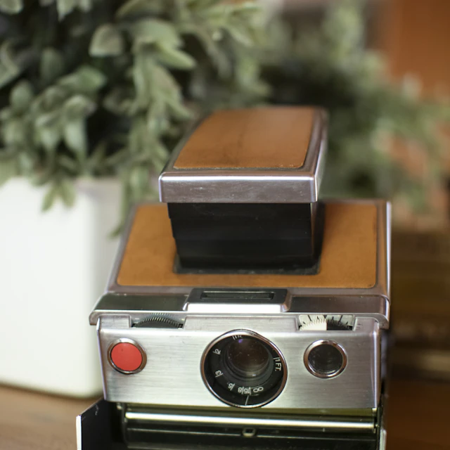 Vintage camera with brown covering and metal trim on a wooden table
