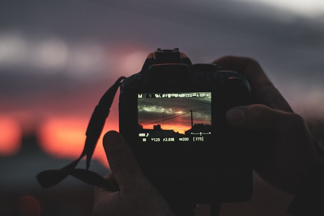 A close-up of a camera lens capturing a vibrant urban scene at sunset.