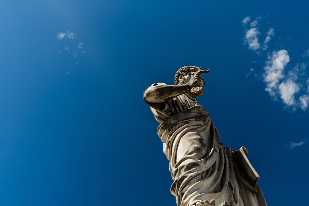 man standing statue under blue and white skies