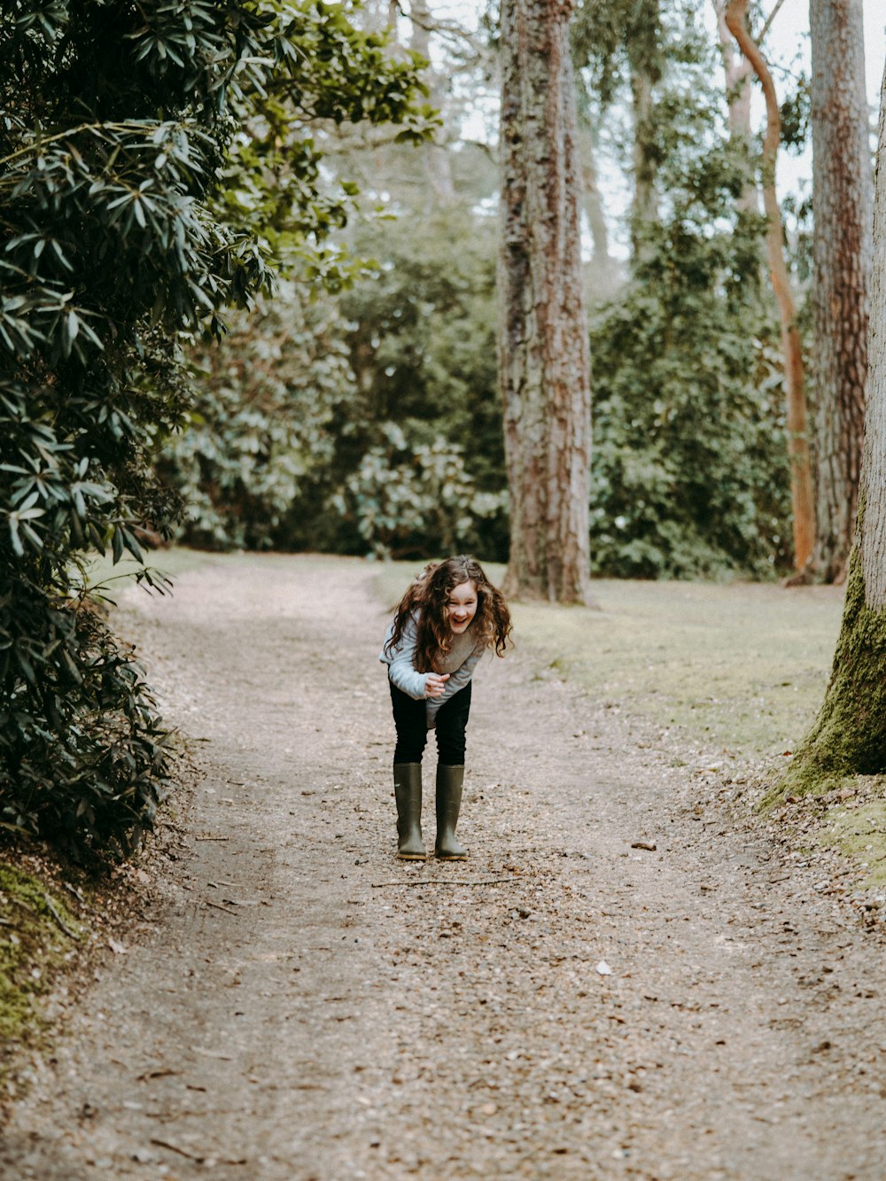 smiling girl standing on dirty road beside tree during daytime