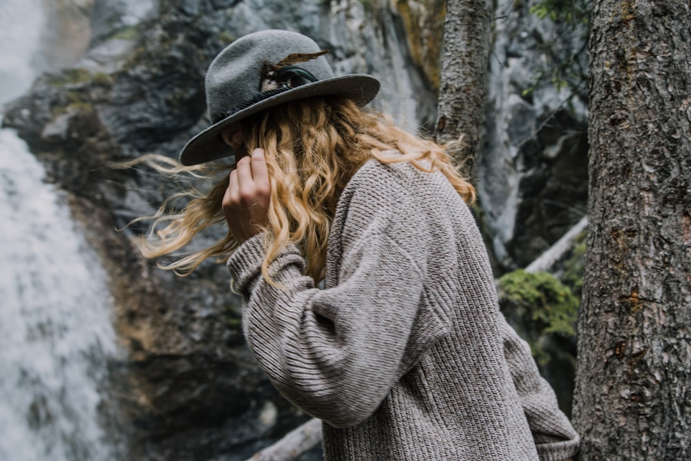 person wearing sweater and black hat looking down near waterfalls