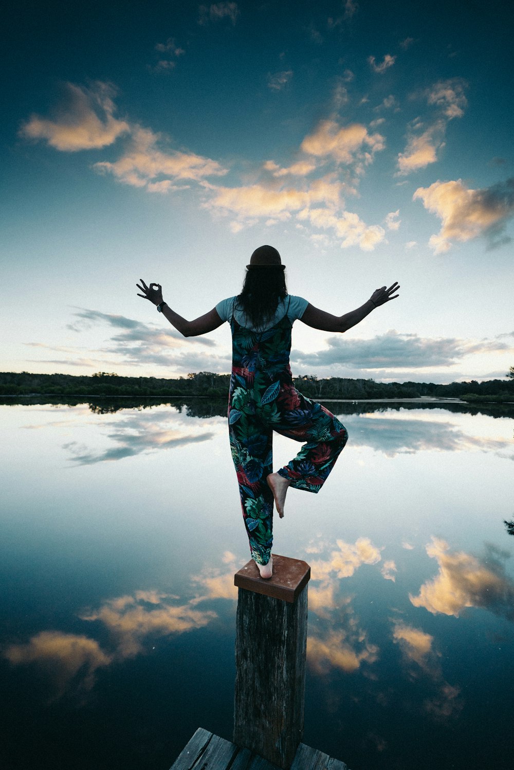 woman standing on one foot on wooden pole