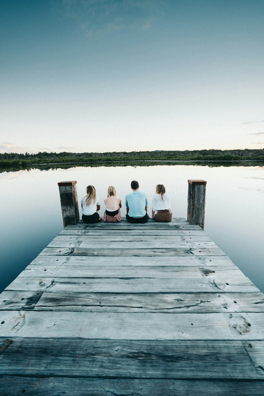 4 person sitting on wooden dock