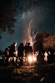 a group of people sitting around a campfire at night