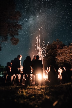 Riders gathered around a campfire under a starry sky, sharing stories and laughter.