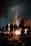 A serene outdoor ceremony with participants gathered around a fire under a starry sky.