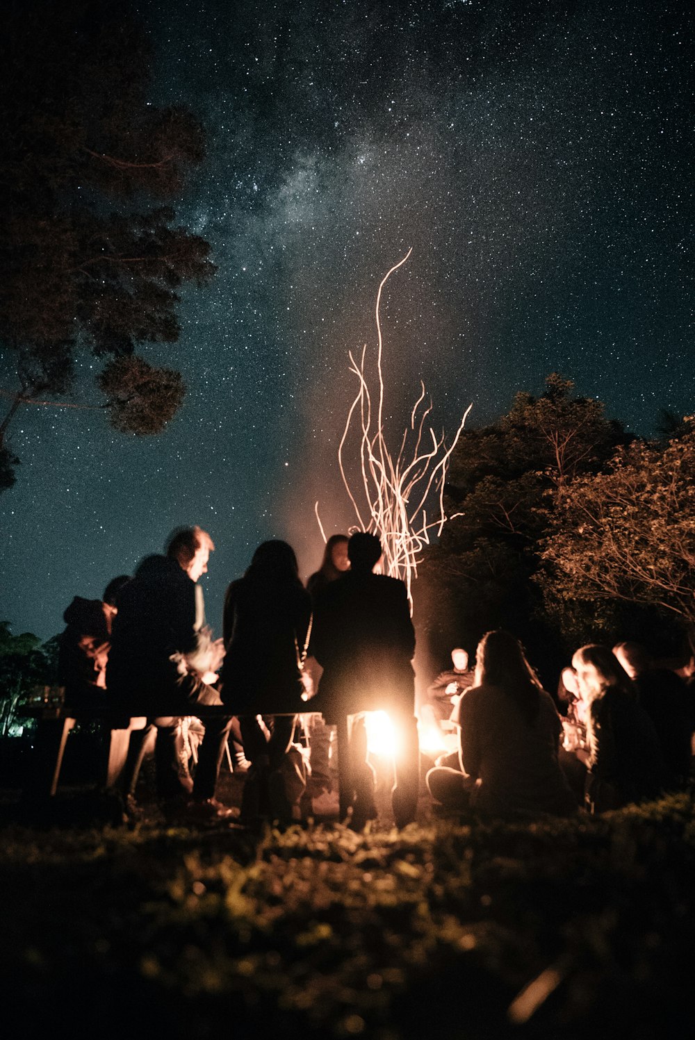 a group of people sitting around a campfire at night