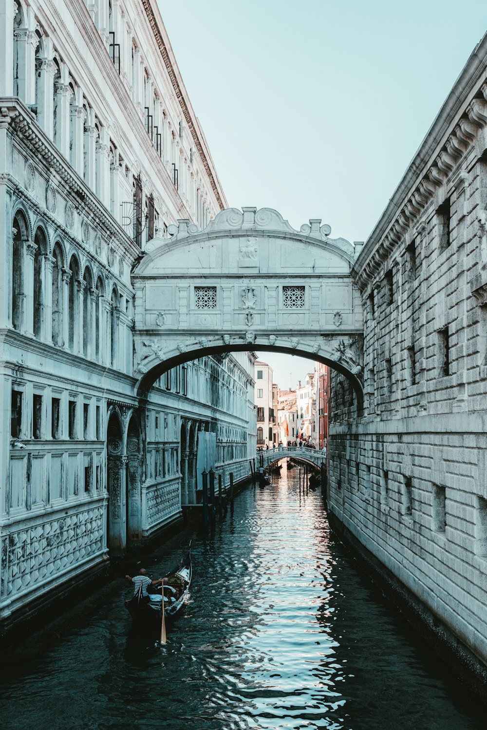 man on boat on canal between buildings