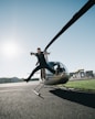 man jumping on pavement near gray helicopter