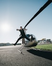 man jumping on pavement near gray helicopter