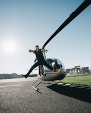 man jumping on pavement near gray helicopter
