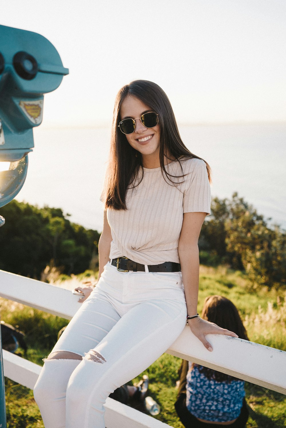 woman wearing pink shirt and white pants sitting on railings