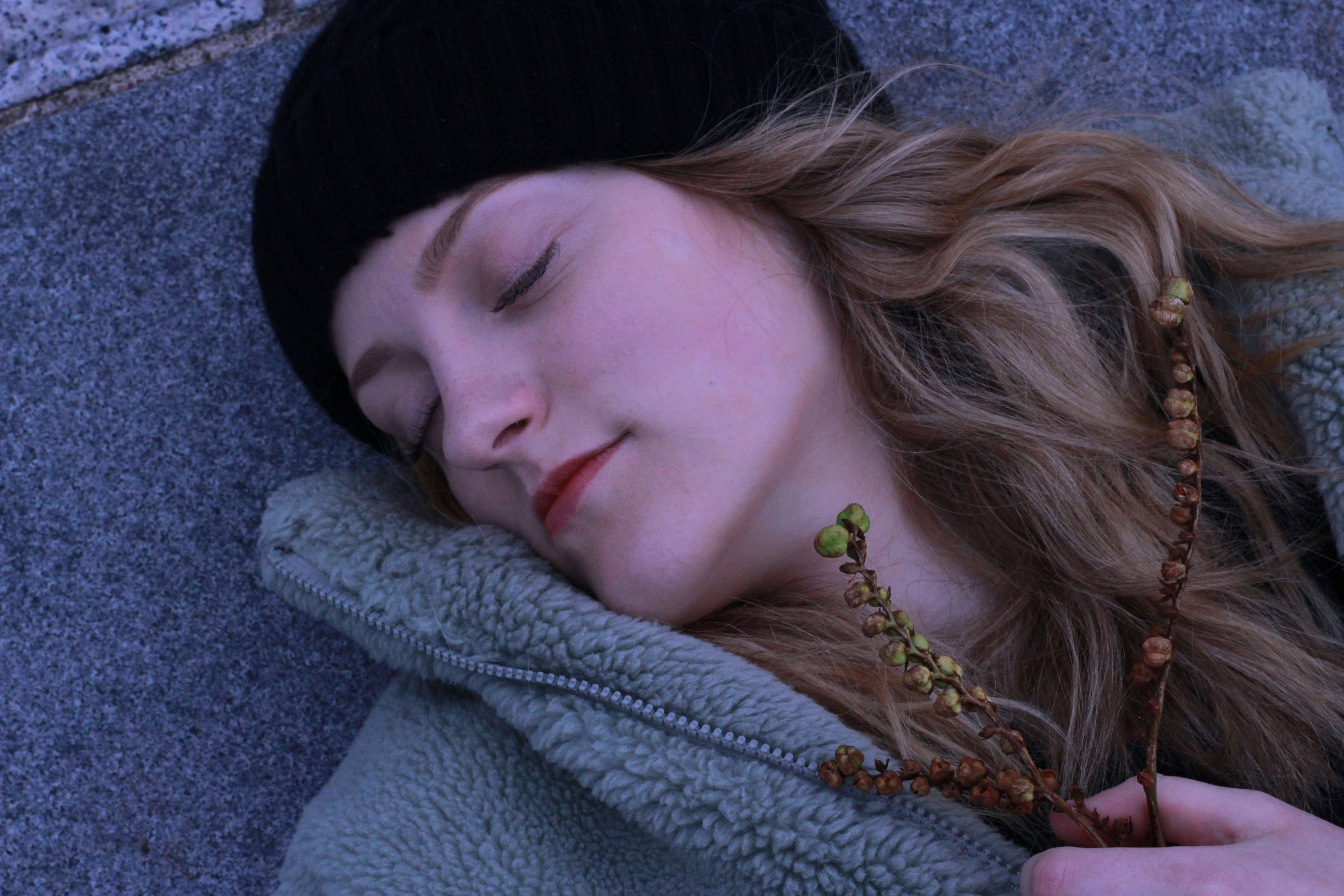 a woman is sleeping on the ground with her eyes closed