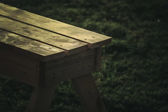 Rustic wooden bench placed in a sunlit garden, highlighting natural wood grain.