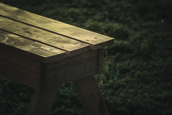 Rustic wooden bench placed in a sunlit garden, highlighting natural wood grain.