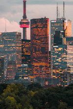 A refined aerial view of Toronto’s skyline at dusk, with the CN Tower illuminated in gold.